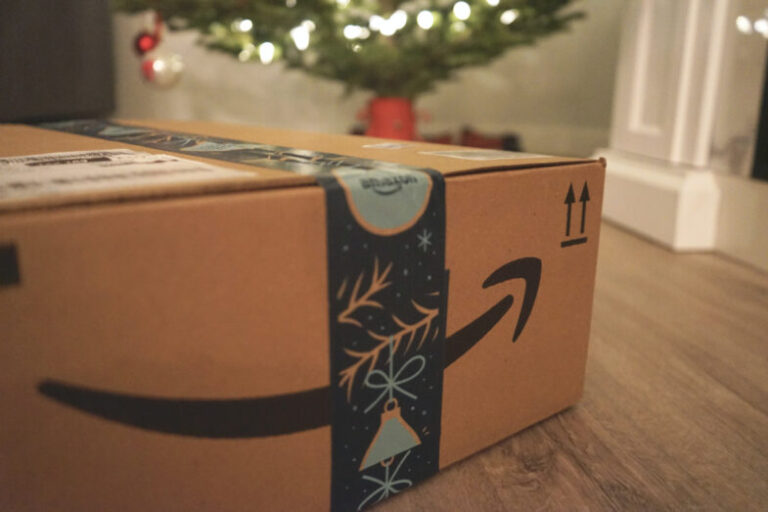 Amazon delivery box with gifts in front of a Christmas tree.